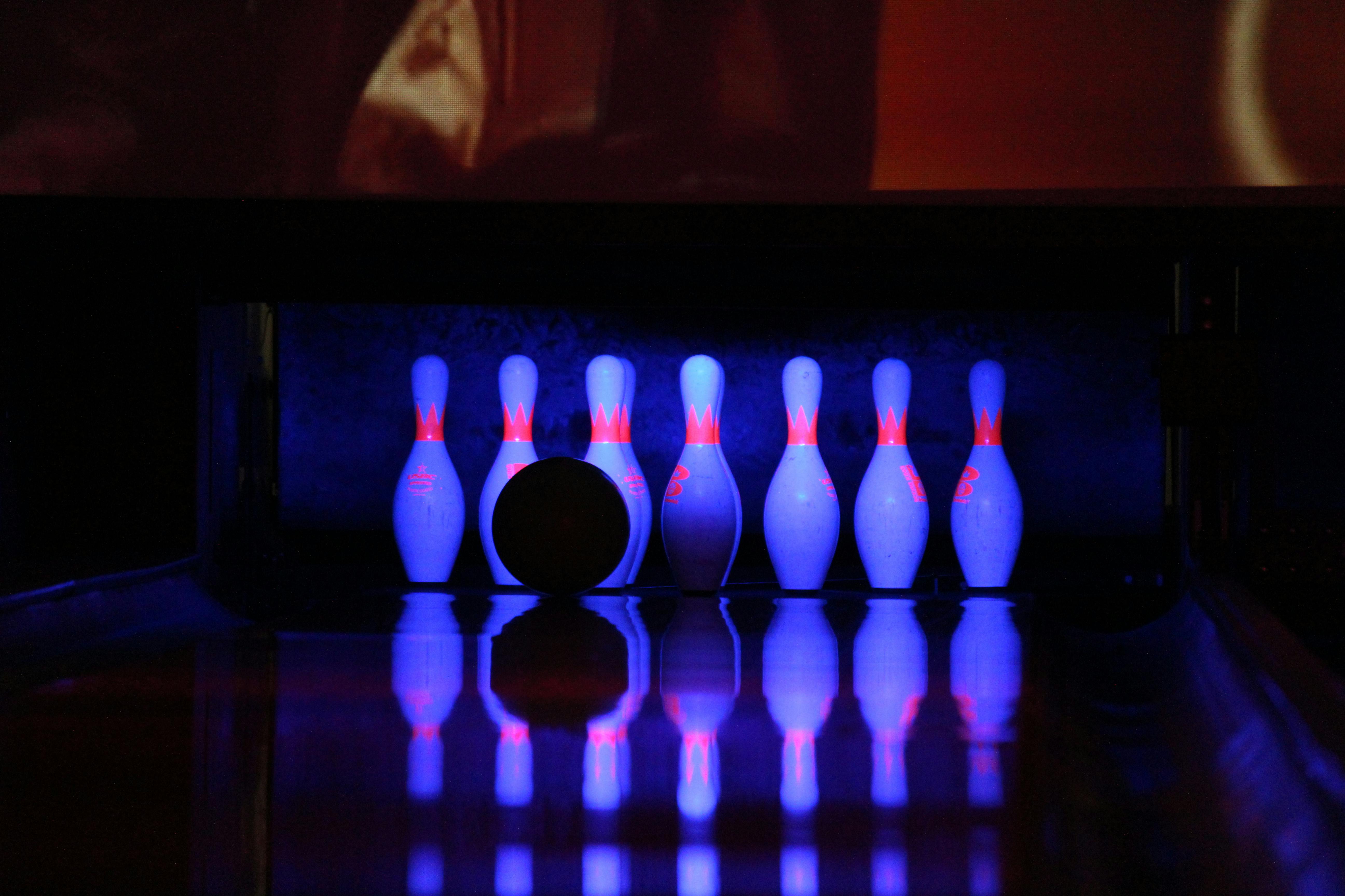 Bowling lane with glowing blue pins and ball, reflected on the lane.