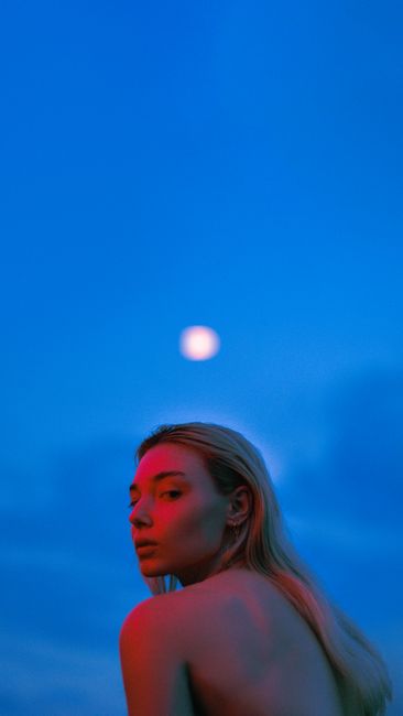 Captivating image of a woman with colorful lighting beneath a moonlit sky.