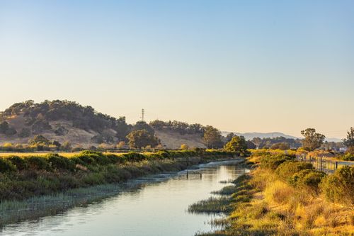 Free Tranquil nature scene depicting a river flowing through hills during an autumn day. Stock Photo