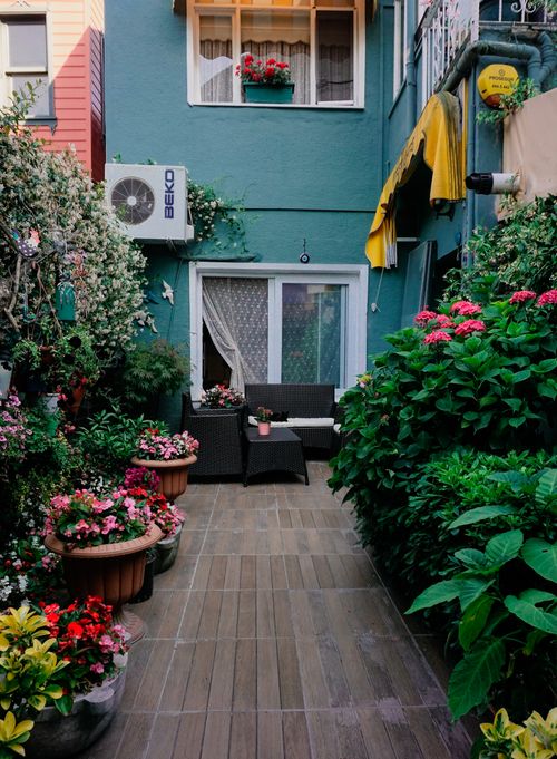 Free Charming urban garden patio with flower pots and seating, perfect for relaxation. Stock Photo