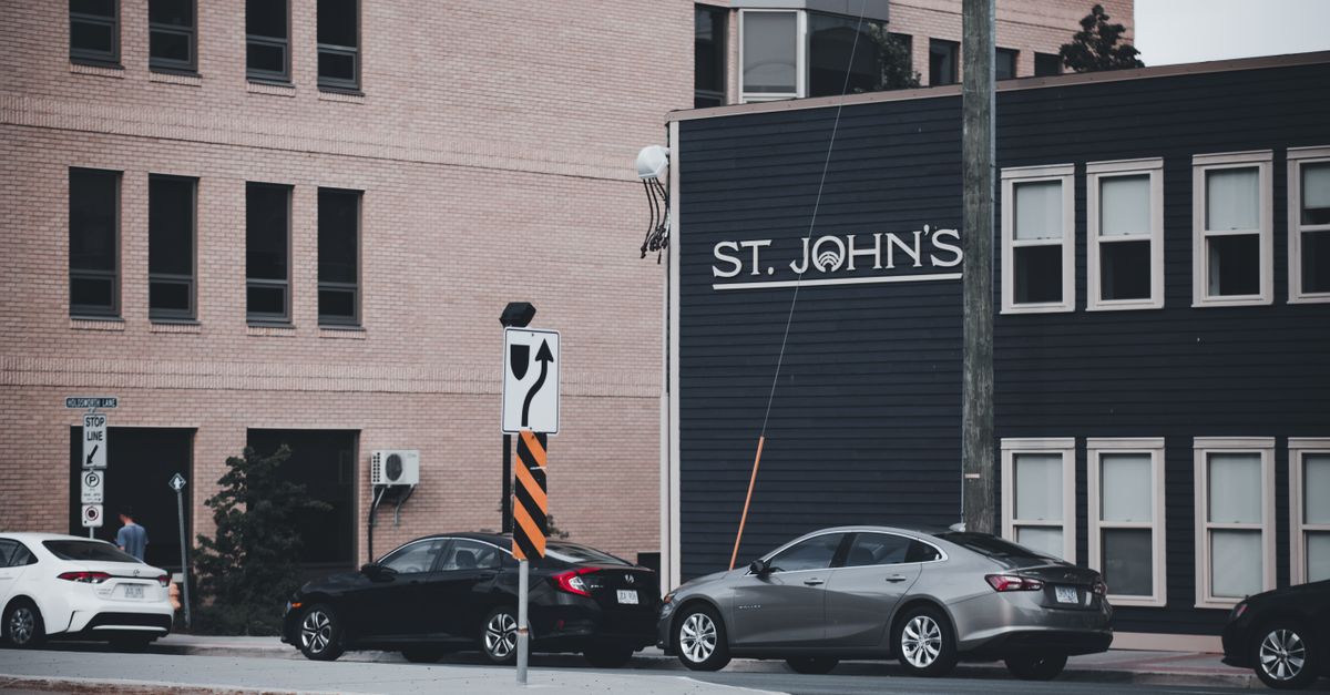 City street view featuring St. John's sign, cars, and urban architecture.