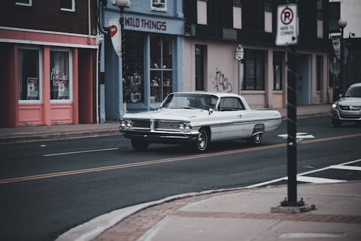 A classic vintage car drives on a city street, capturing an urban nostalgic vibe.