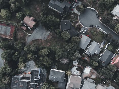 Drone shot capturing a top-down view of a suburban neighborhood with houses, streets, and greenery.