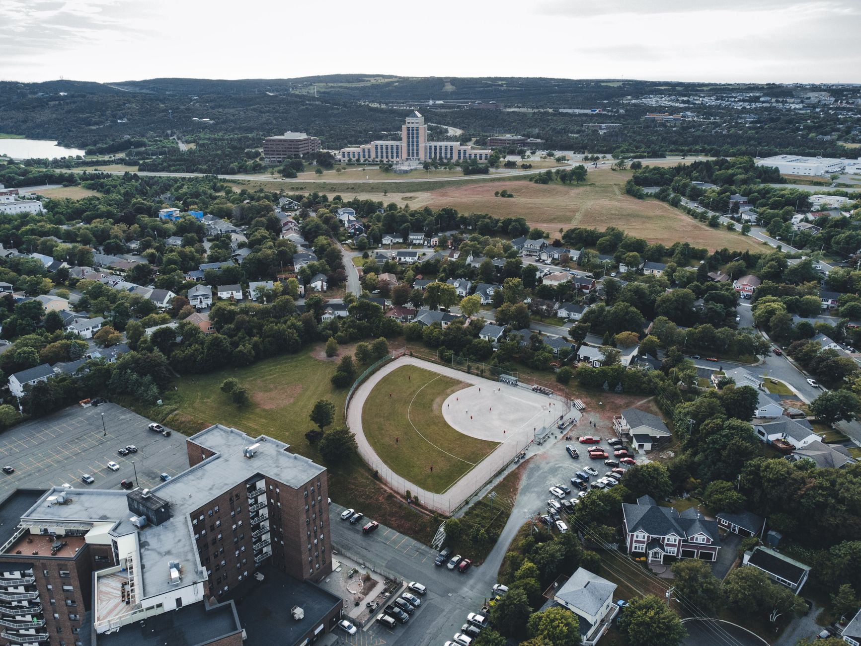 Aerial shot of a cityscape with buildings, park, and open fields, showcasing urban planning.