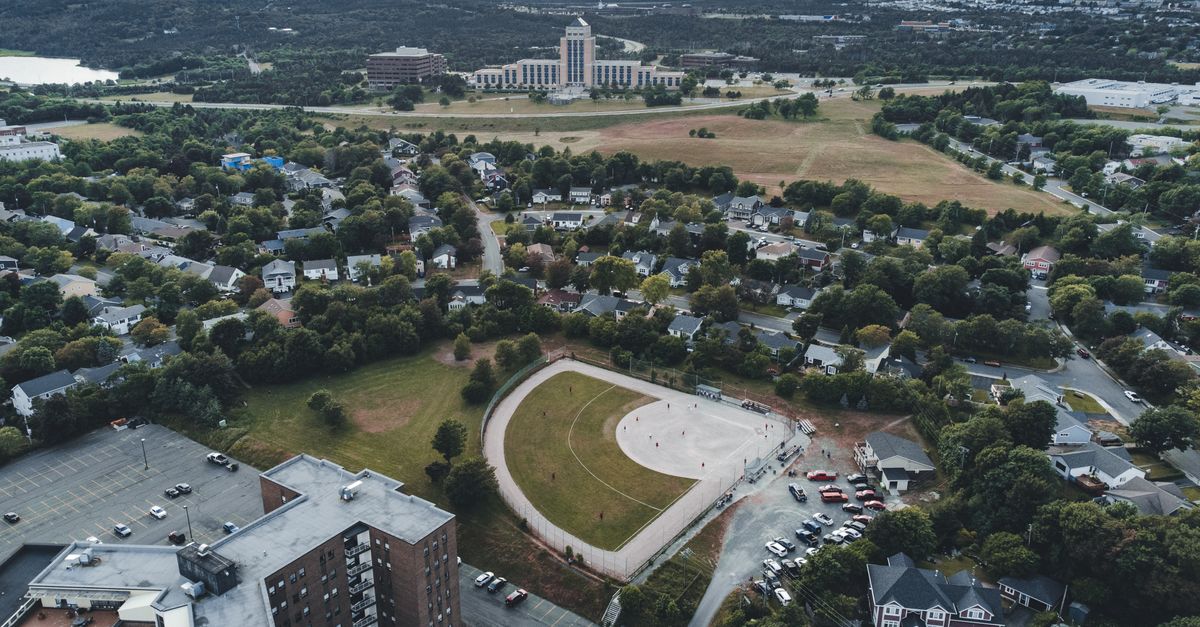 Aerial shot of a cityscape with buildings, park, and open fields, showcasing urban planning.
