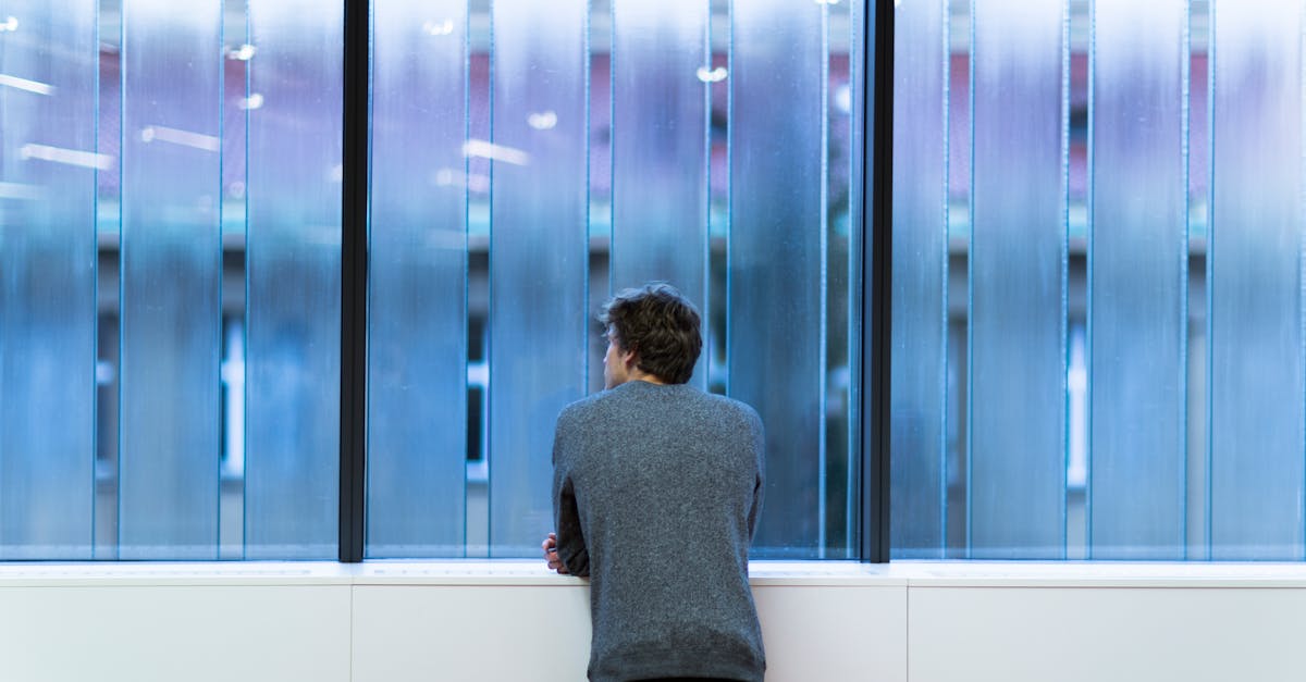 Man Standing and Facing on Glass Wall