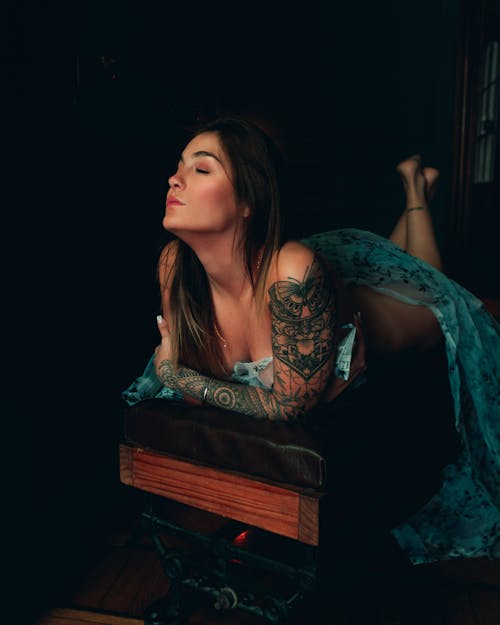 A Tattooed Woman Lying Down with Her Head Up and Eyes Closed