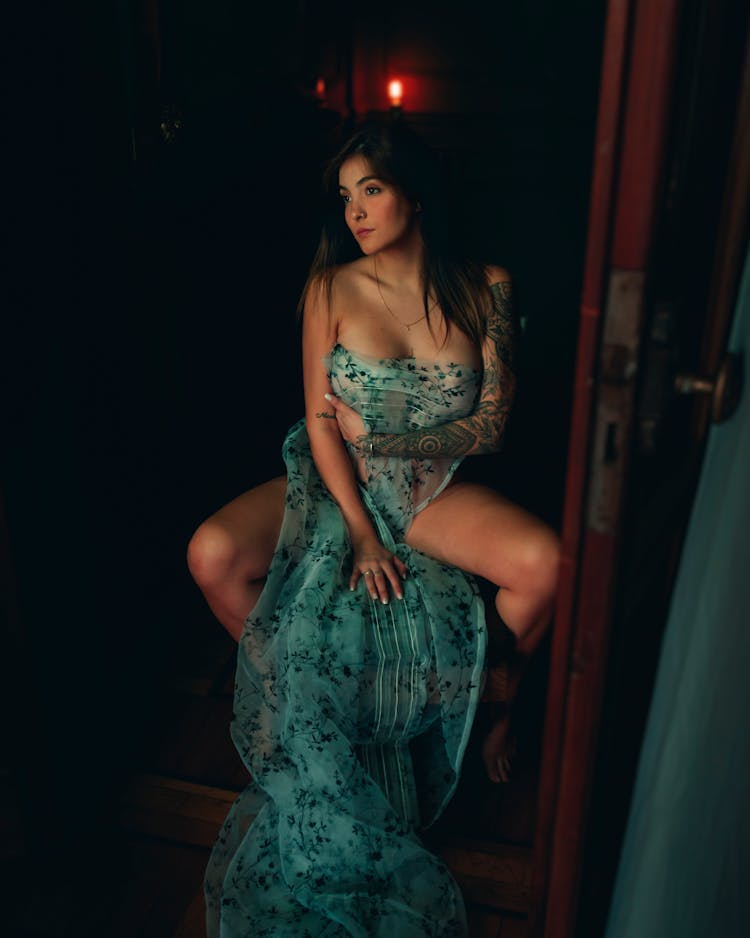 A Woman Sitting Near Door Covering Her Nude Body With A Green Sheer Fabric