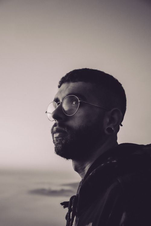 Free Close-up sepia portrait of a thoughtful man with beard and eyeglasses, looking away. Stock Photo