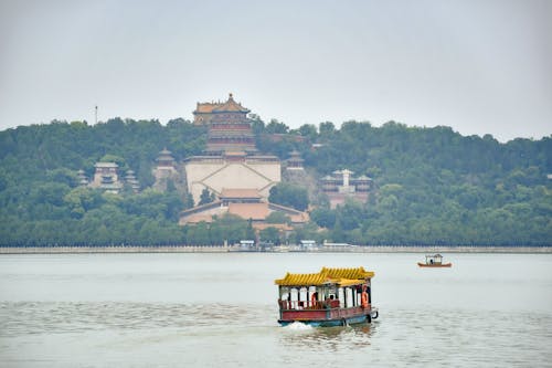 Pagoda Shape Boat on a River and Traditional Asian Architecture on a Hill
