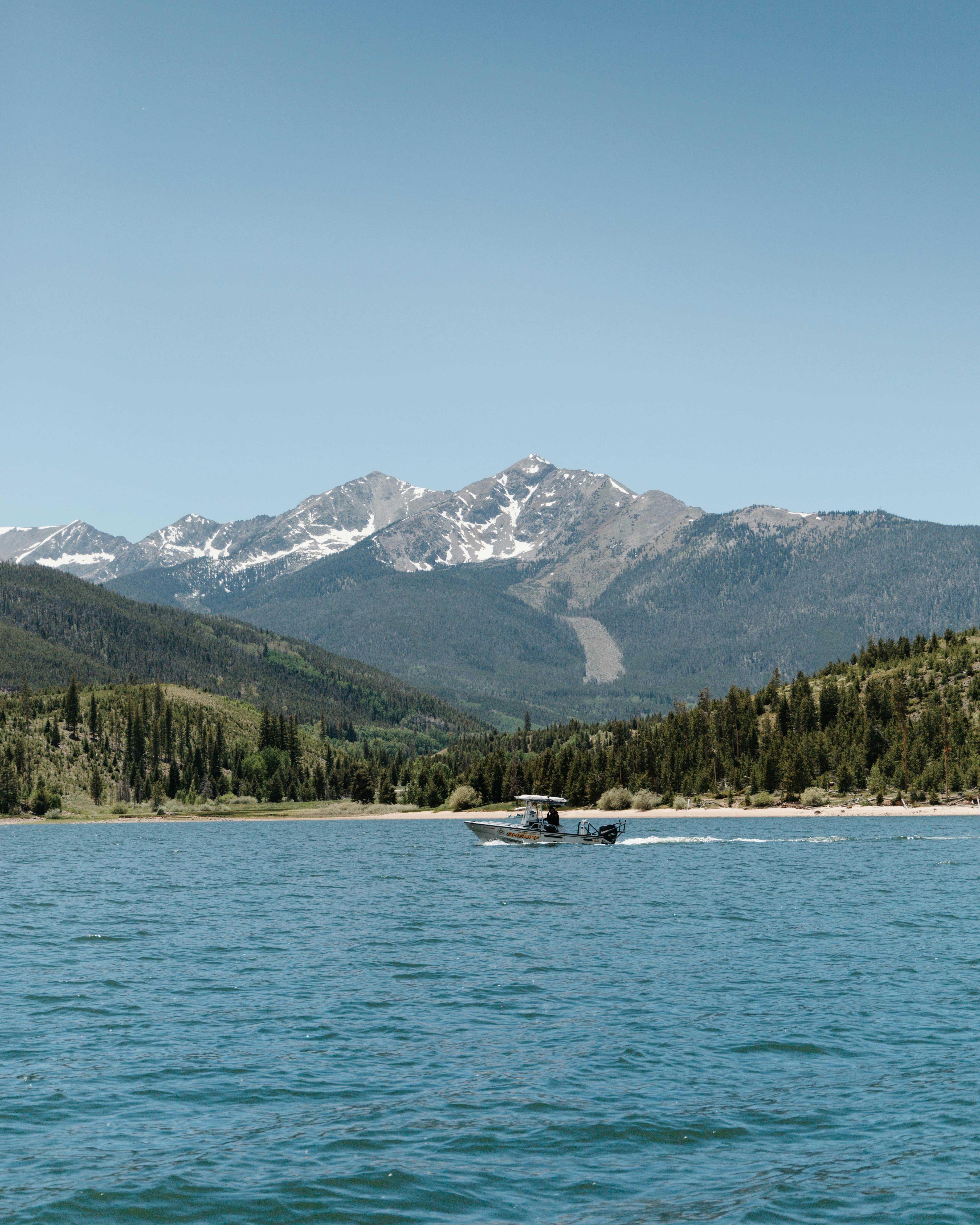 a boat sailing on the river near green trees