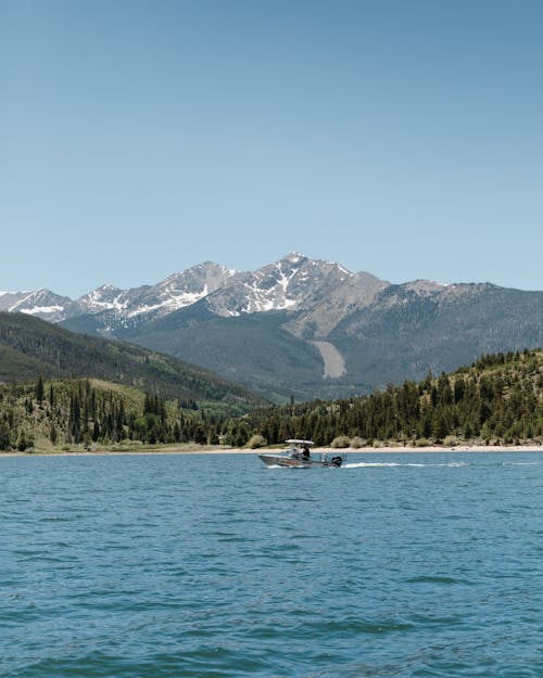 Free A Boat Sailing on the River Near Green Trees Stock Photo