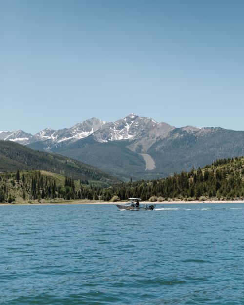 Free A boat sailing on a clear mountain lake with scenic mountain views and blue sky. Stock Photo