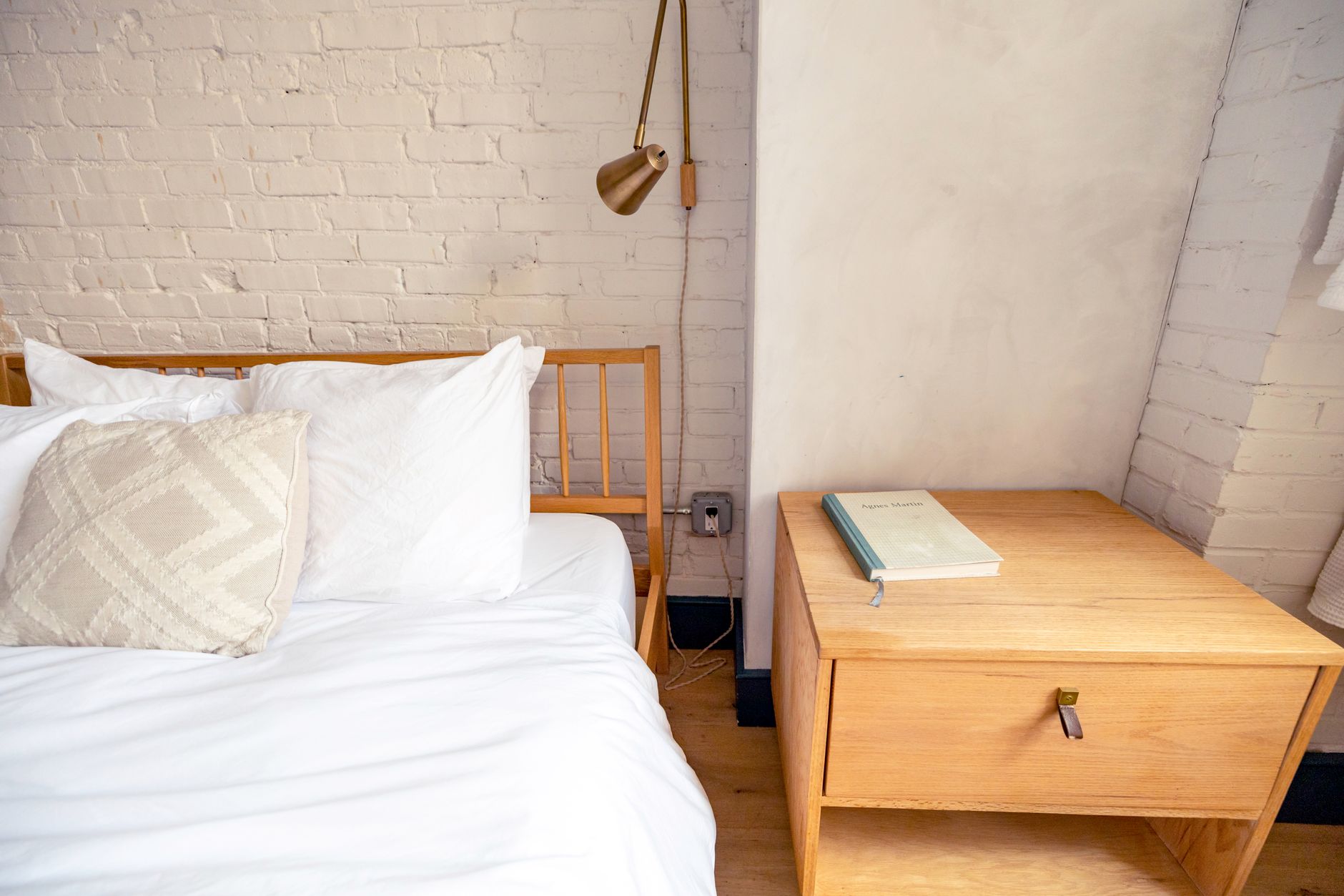 wooden nightstand with a glass of water, natural sleep supplement, and a soft glowing lamp in a calm bedroom setting
