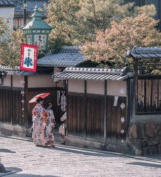 在日本京都的一条传统街道上，两名穿着和服的妇女正走着，展示着日本文化