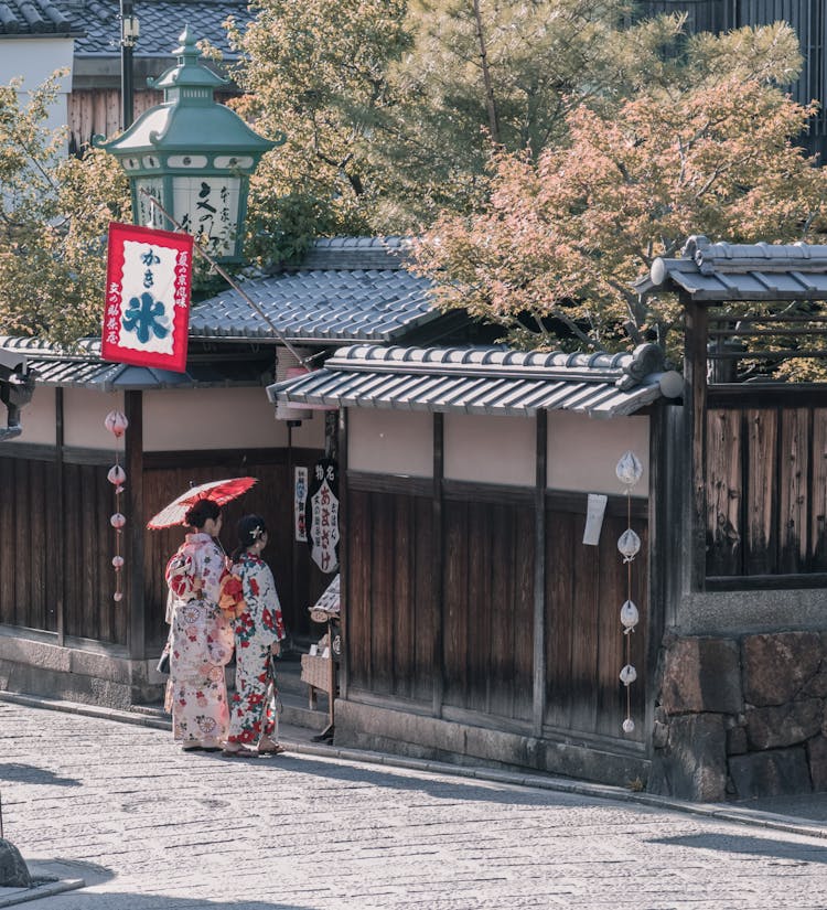 Two Women Wearing Traditional Dresses Standing Near House