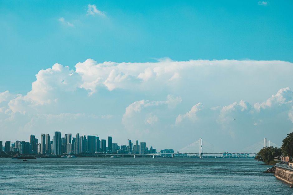 Panoramic view of a city's skyline featuring a bridge and river beneath a stunning blue sky.