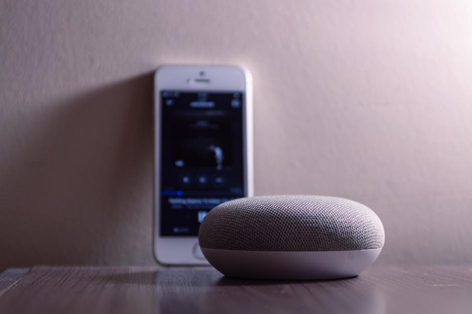 Google Home Pod sitting next to an iPhone on a table