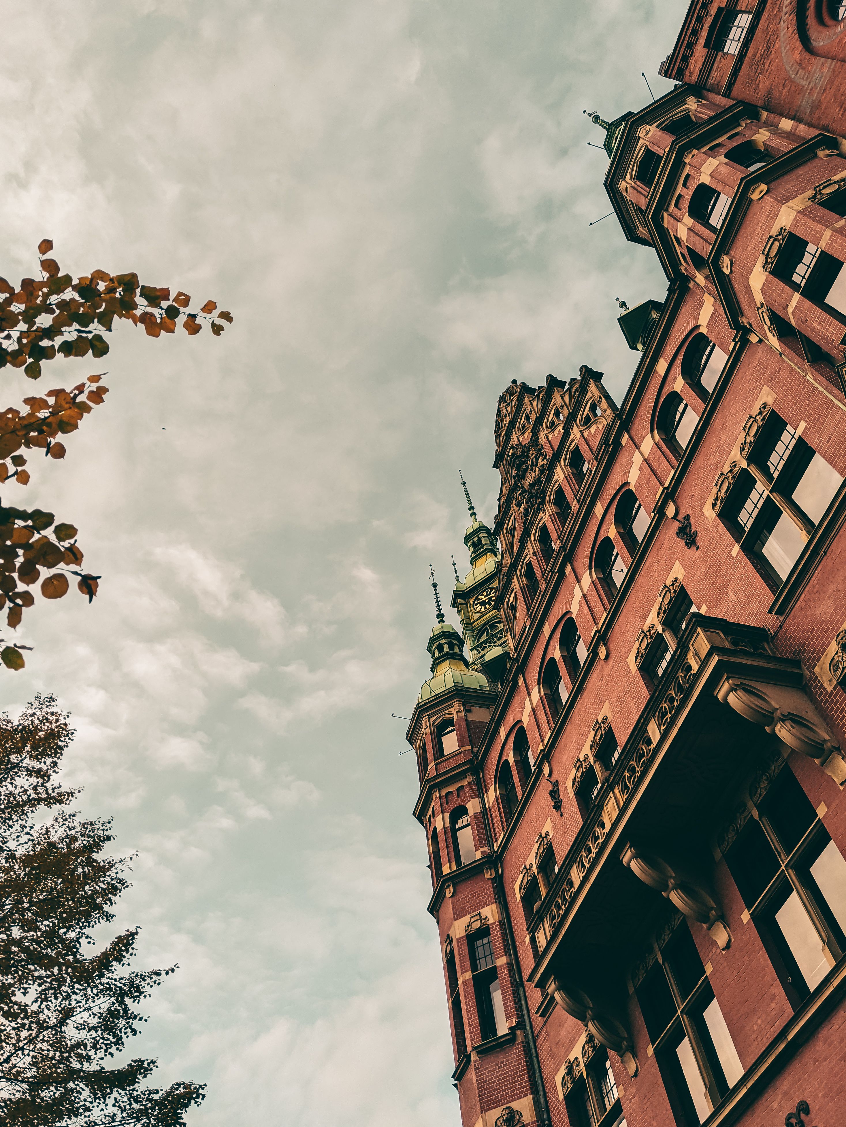 Low Angle Shot of Brown Brick Building Under Cloudy Sky · Free Stock Photo
