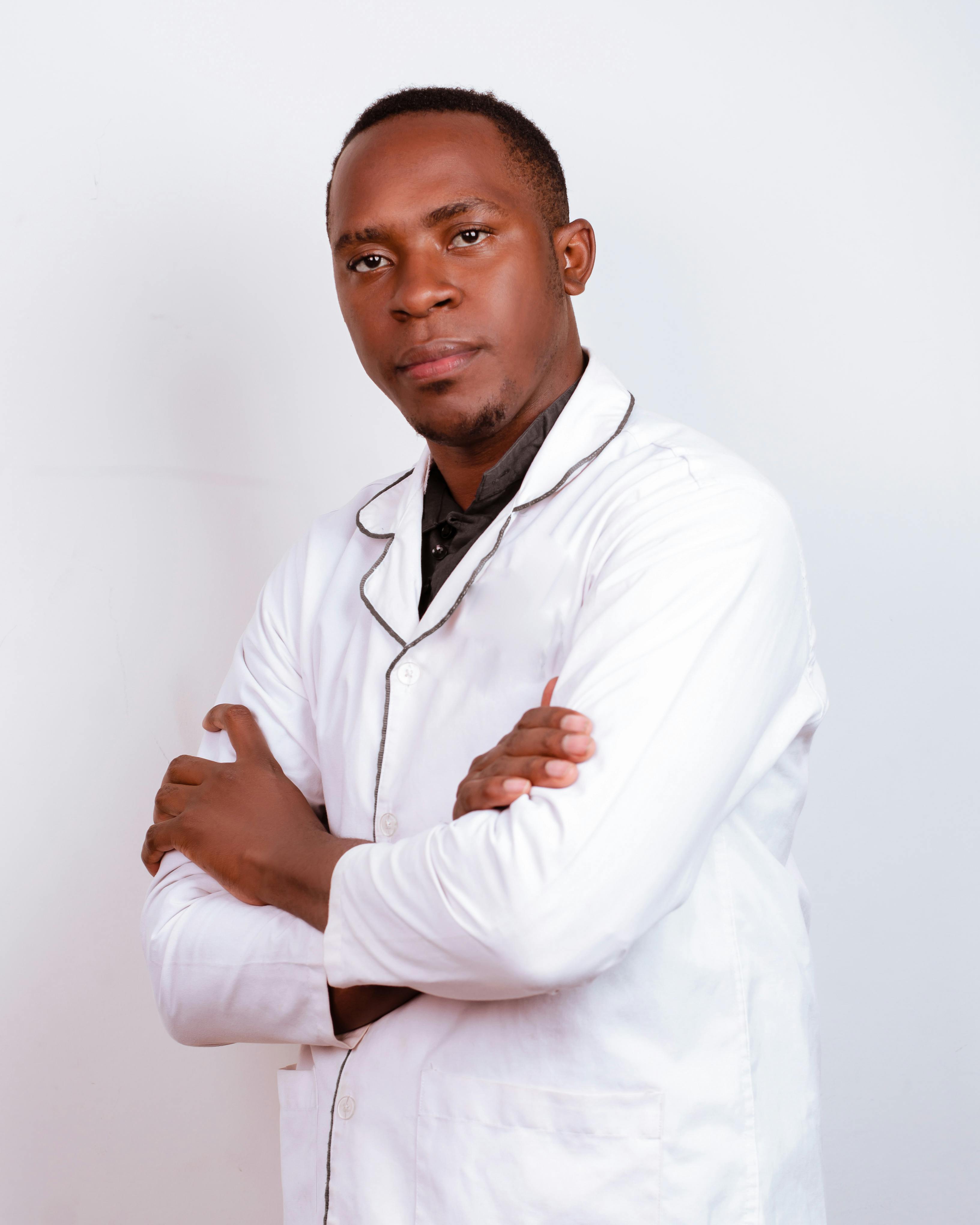 African doctor confidently posing with arms crossed, symbolizing professionalism and care.