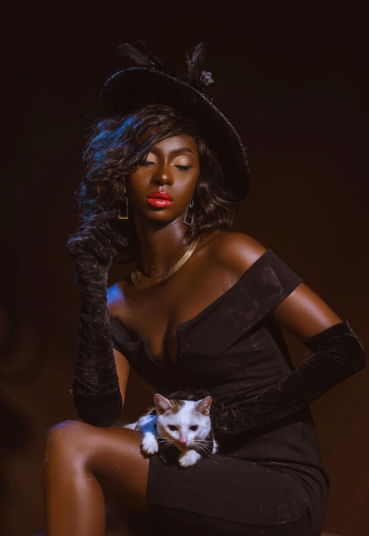 Woman Fashion Model In Black Tight Dress Holding Cat On Knees