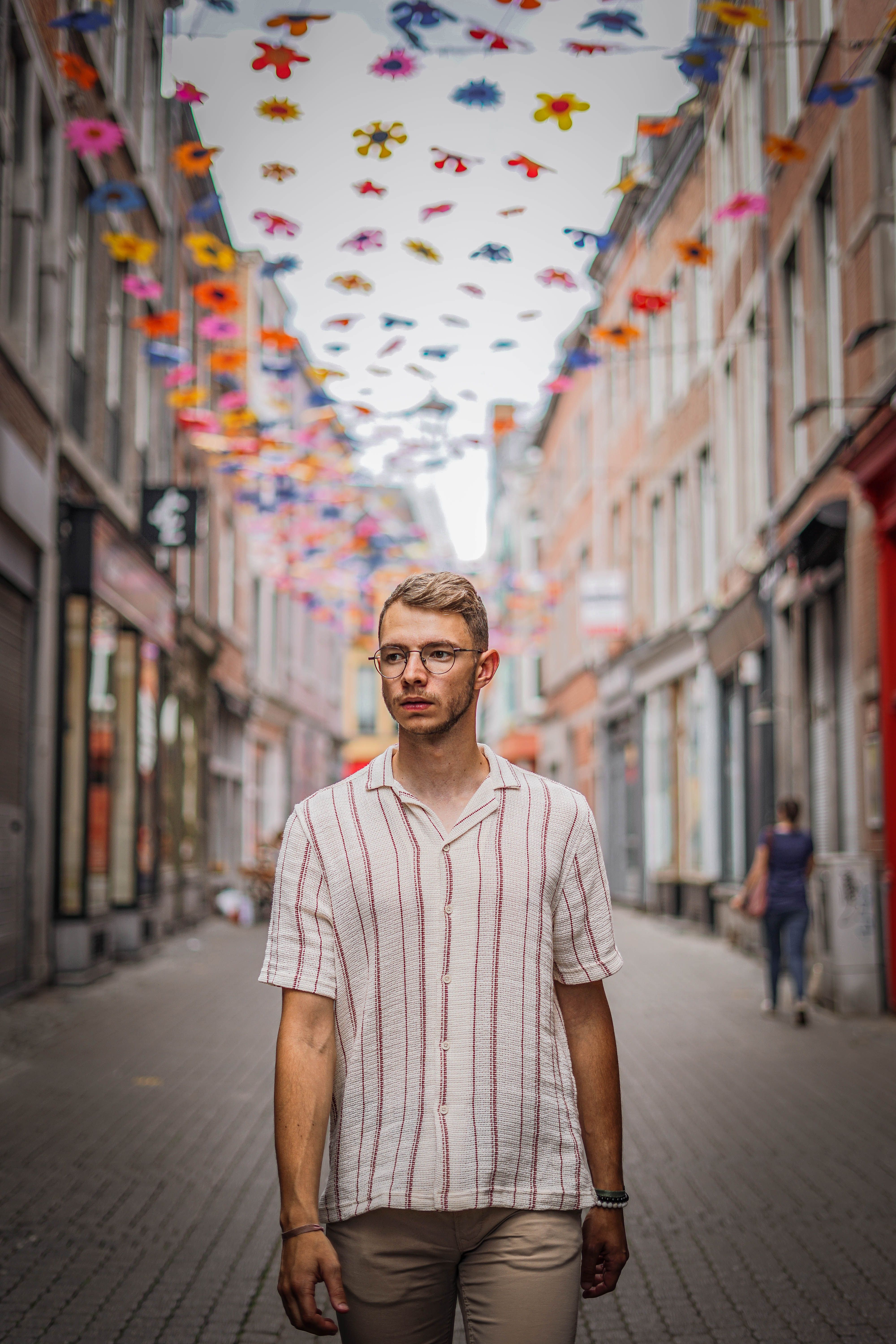 Young man strolling in a vibrant, decorated street of Namur, Belgium.