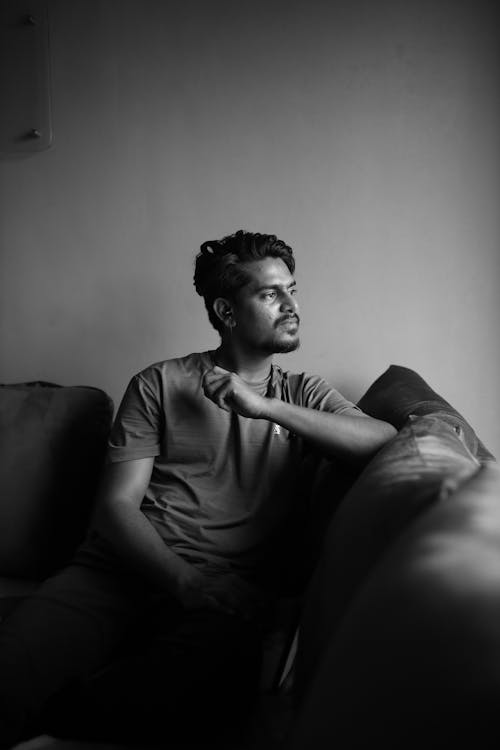 Grayscale Photo of a Man Sitting on the Couch