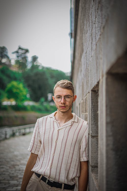 A Man in a Striped Shirt Leaning on a Wall