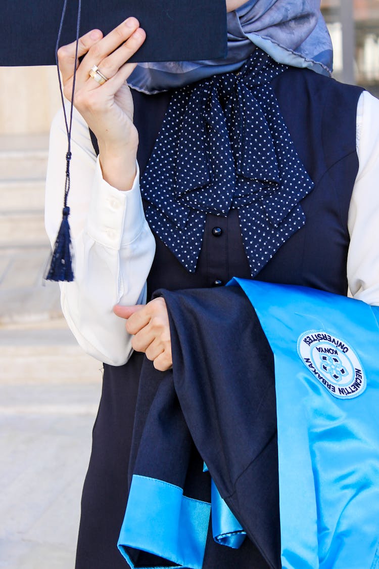 Woman Holding Graduation Cap And Robe