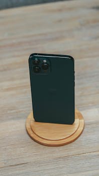 Green smartphone elegantly displayed on a round wooden stand, capturing minimalistic elegance.
