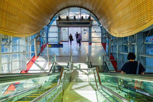 Free Sunlit view of a modern Dubai Metro station with escalators and passengers in motion. Stock Photo