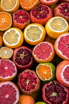Colorful close-up of sliced citrus fruits and pomegranates in a vibrant arrangement, perfect for food enthusiasts.