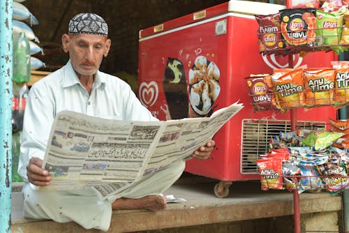 Free A Man Reading a Newspaper in a Store Stock Photo