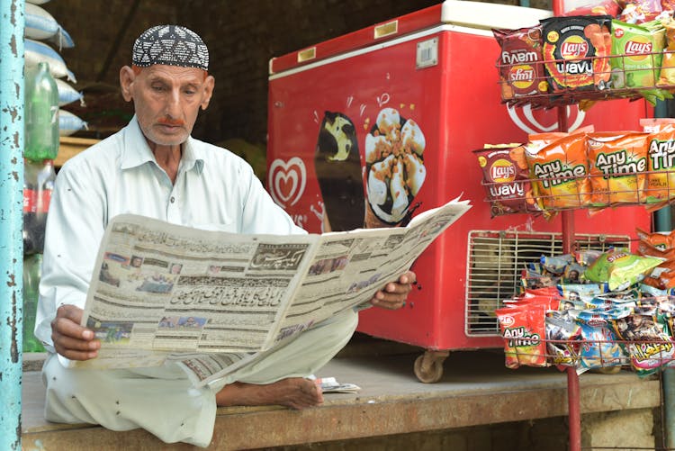 A Man Reading A Newspaper In A Store