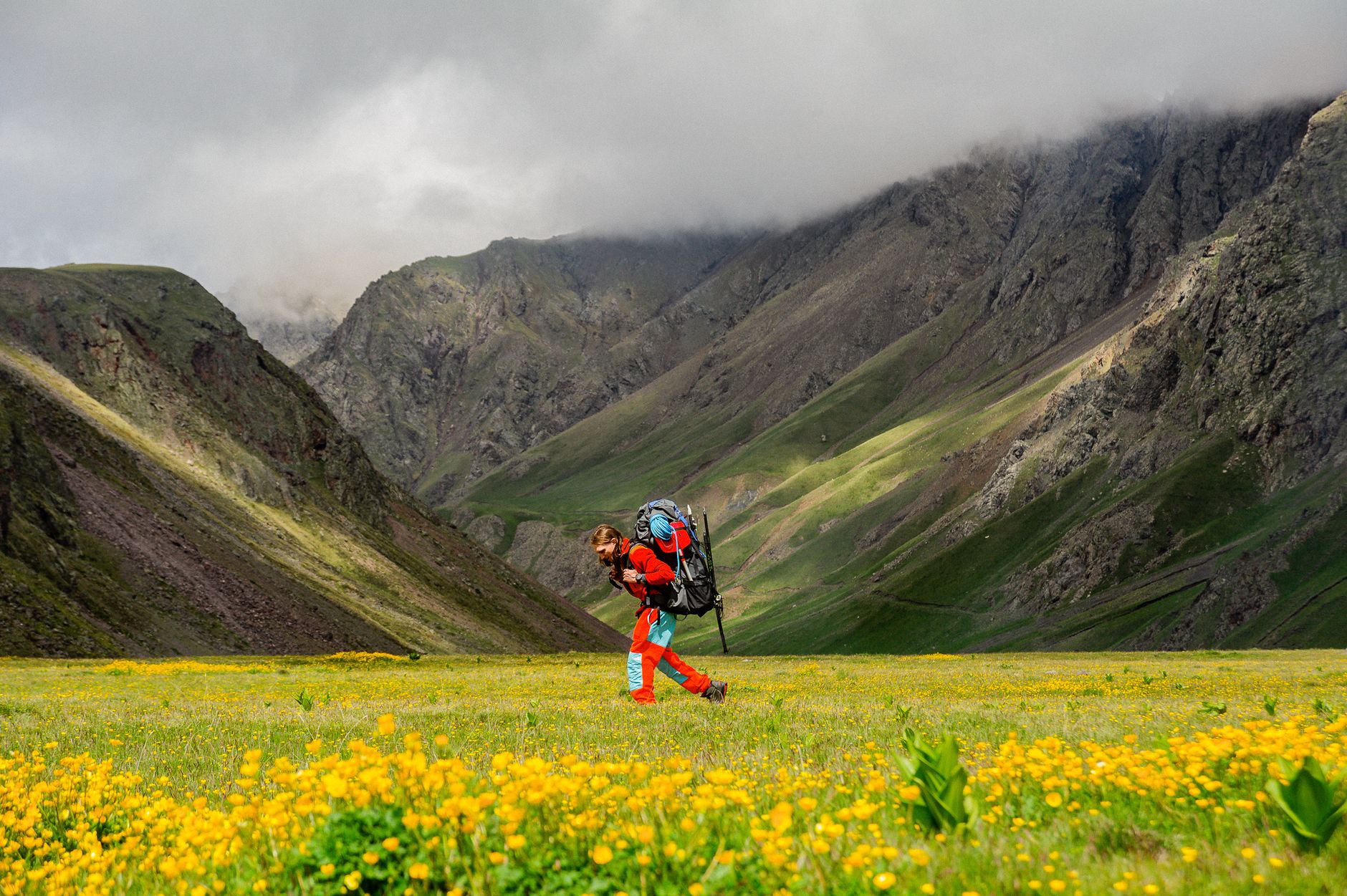 Woman hiking in vibrant mountain scenery with backpack, surrounded by nature.