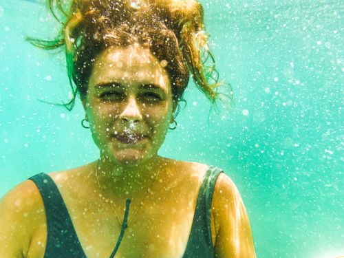 Free A woman smiling underwater surrounded by bubbles in clear turquoise water. Stock Photo