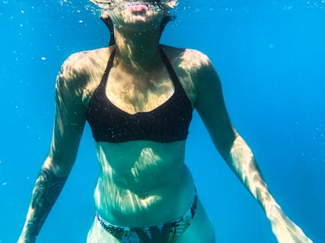 Stylish underwater portrait of a woman in a black bikini top swimming effortlessly.