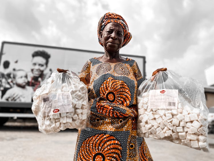 Old Woman In Traditional Dress With Bags Of Food