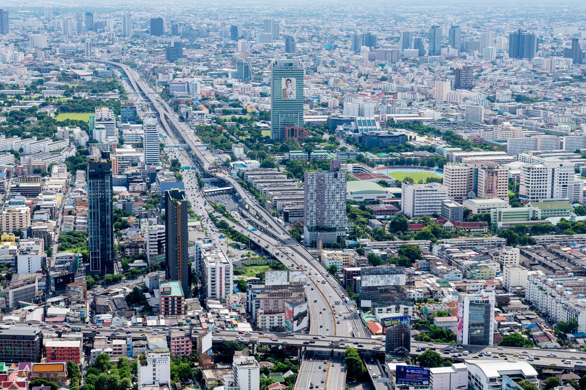Aerial view of bustling Bangkok cityscape featuring modern skyscrapers and highway.