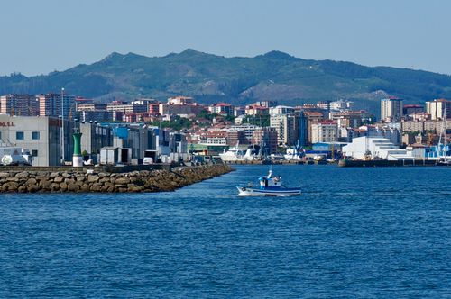 Free A picturesque boat floating in Vigo harbor with a backdrop of the city's vibrant skyline. Stock Photo
