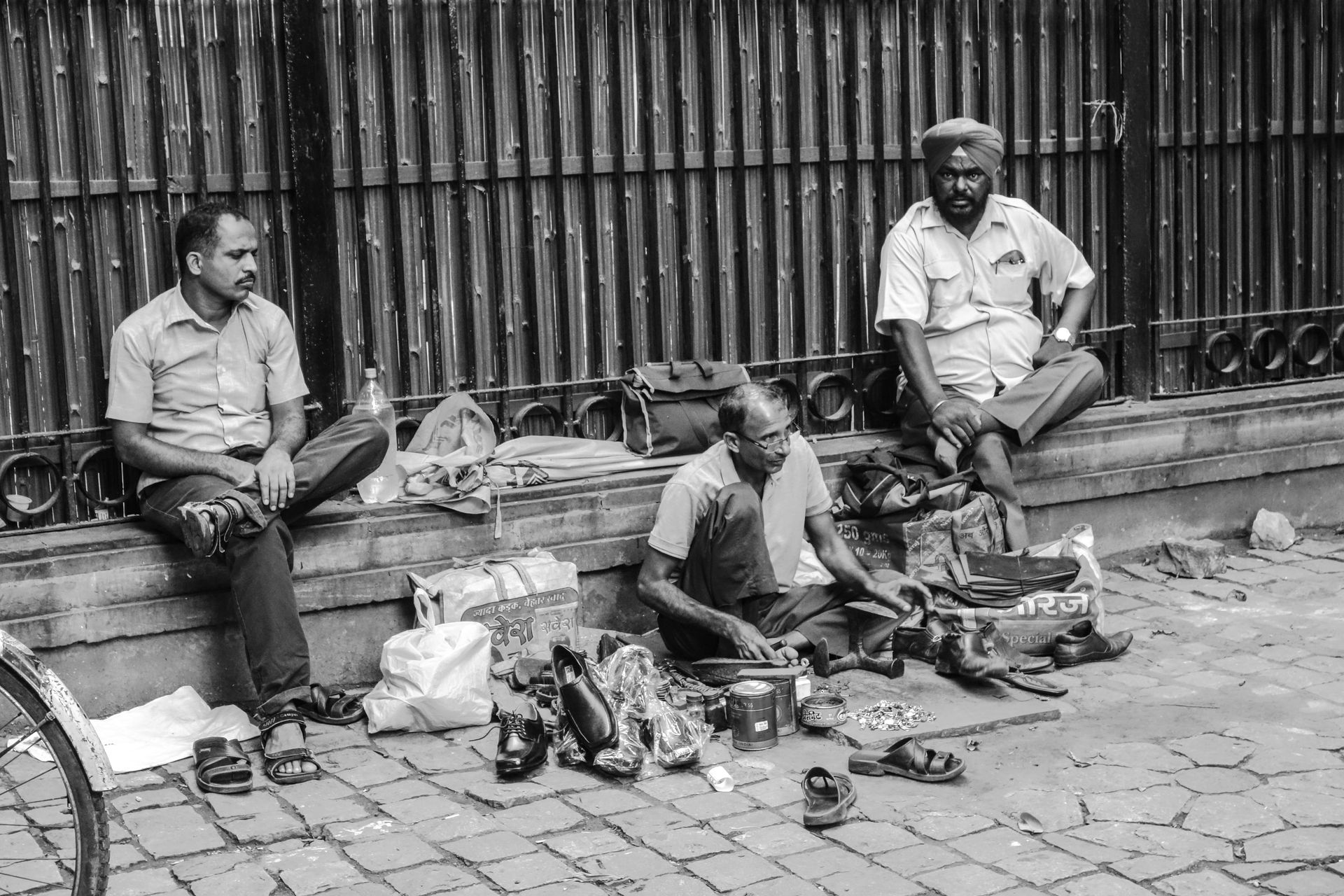 A candid black and white capture of local men working and resting at a street market in New Delhi.