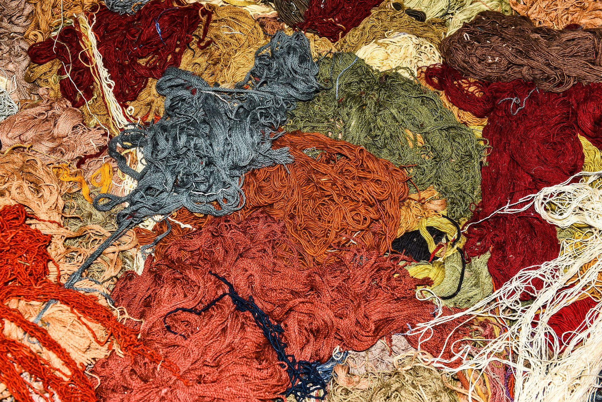A close-up view of assorted colorful yarn threads in various textures and shades.