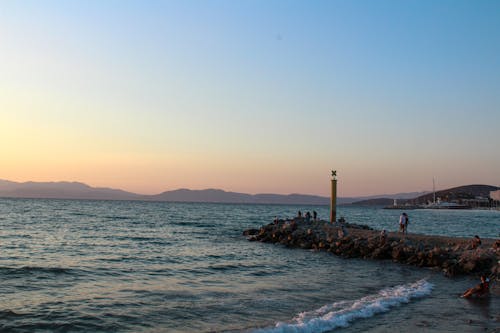 Foto profissional grátis de alvorecer, beira-mar, colinas