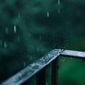 Close-up of raindrops splashing on a metal railing during a rainy day in Russia.