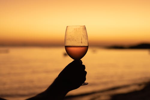 A Person Holding a Wine Glass During Sunset