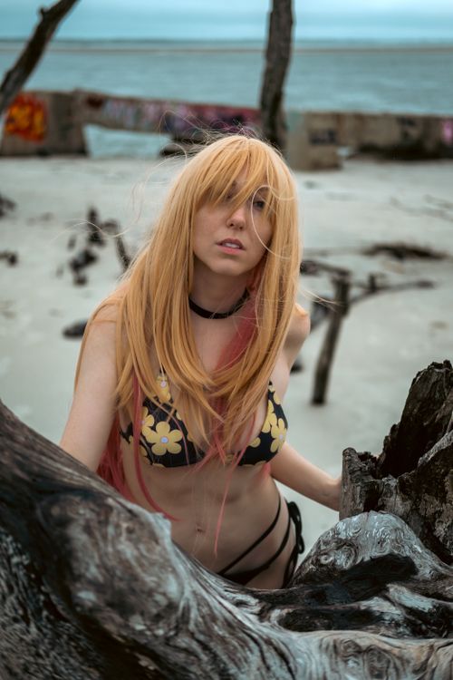 Free Stunning beach photoshoot with a blonde woman in a floral bikini and long hair. Stock Photo