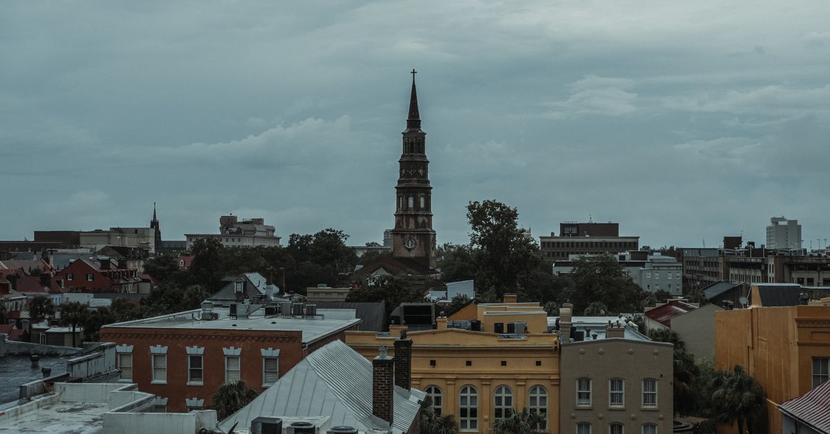 Captivating view of a historic bell tower amidst an urban cityscape under overcast skies.