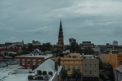 Free Captivating view of a historic bell tower amidst an urban cityscape under overcast skies. Stock Photo