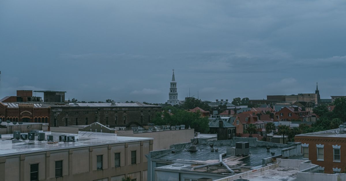 A cloudy Charleston cityscape featuring St. Michael's Church and urban architecture.