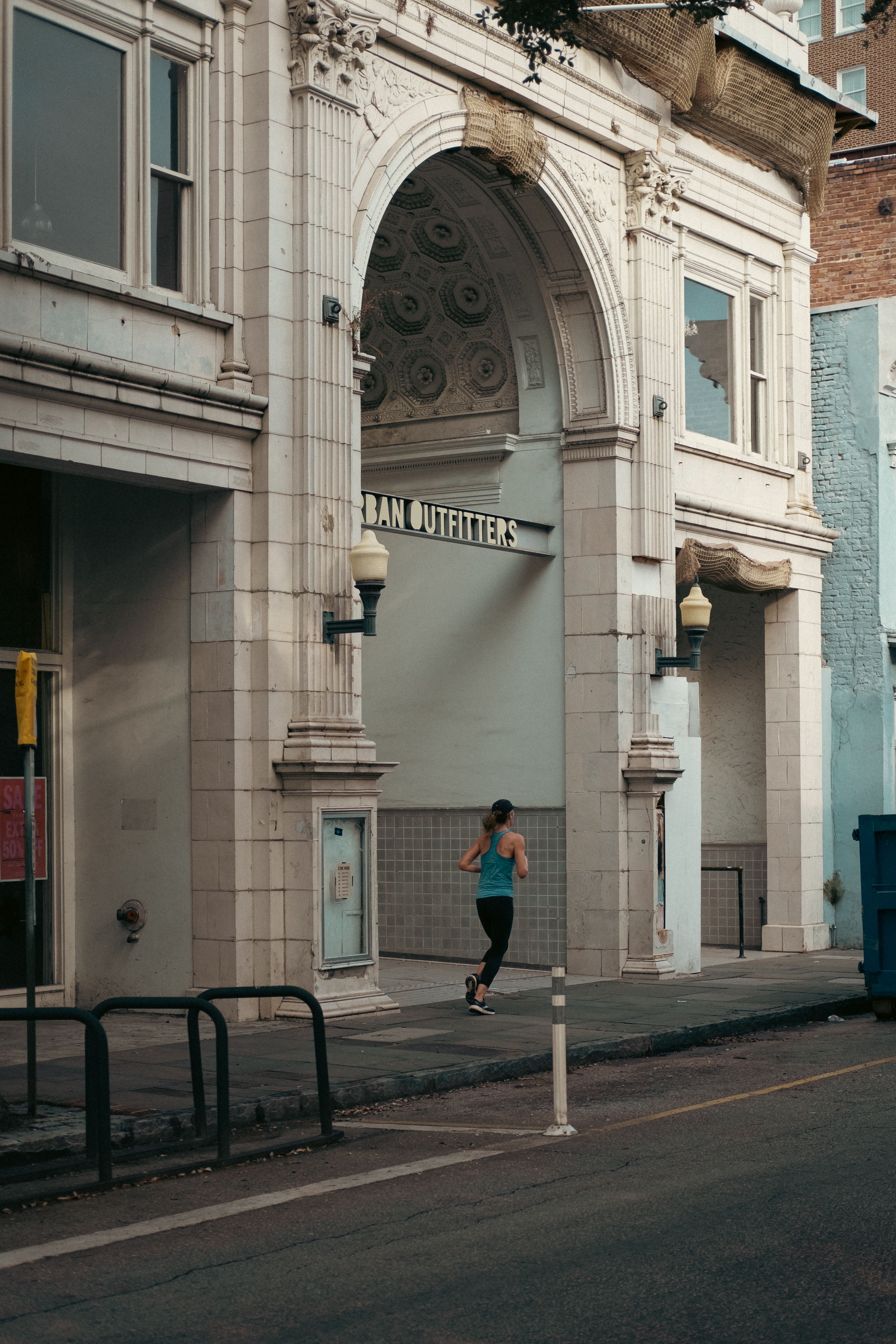 Woman jogging outside historic baroque building with arches - running club history routes